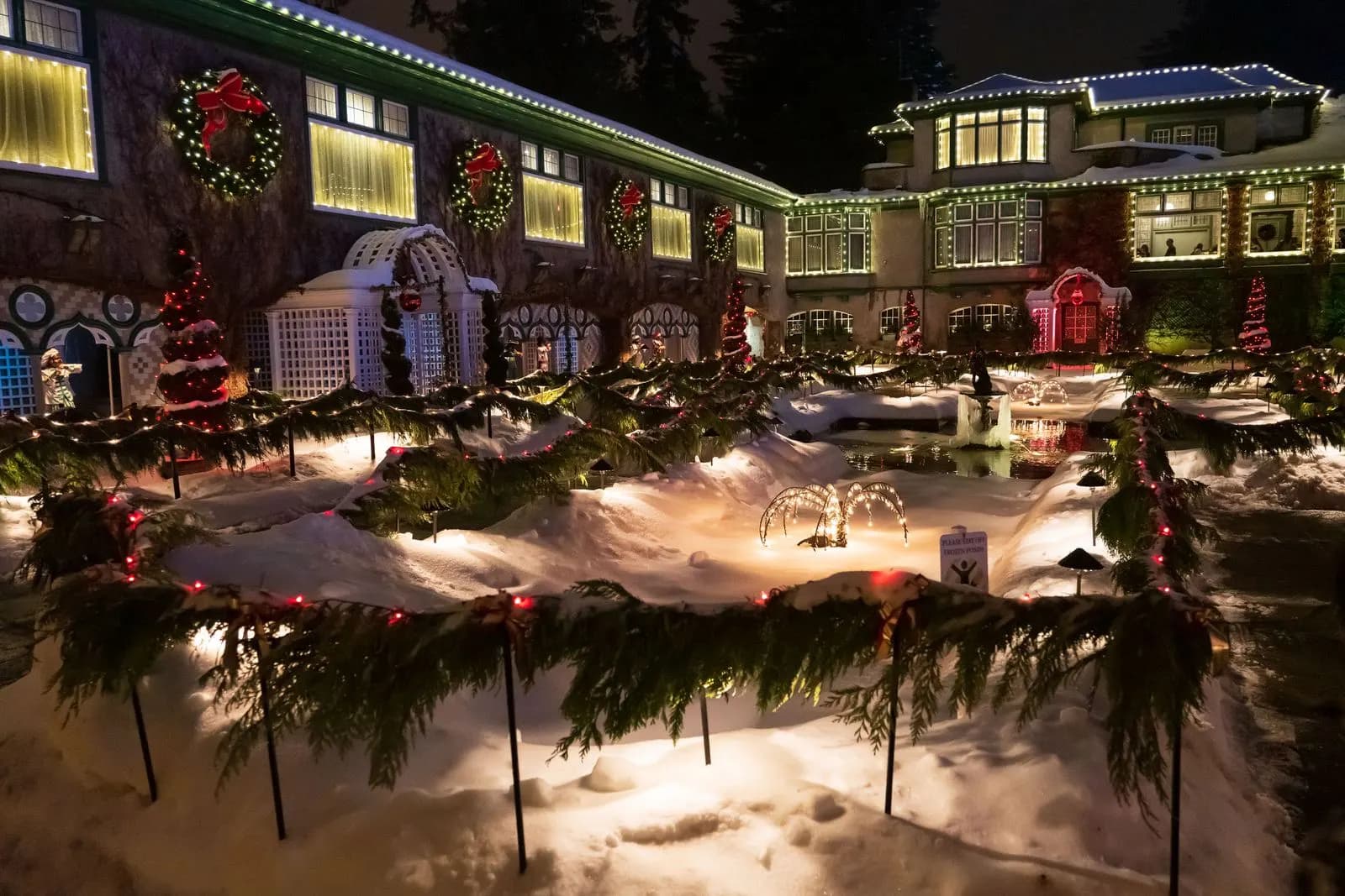Example of a large building with lit wreaths in every window, roofline lights and lit garland along the paths