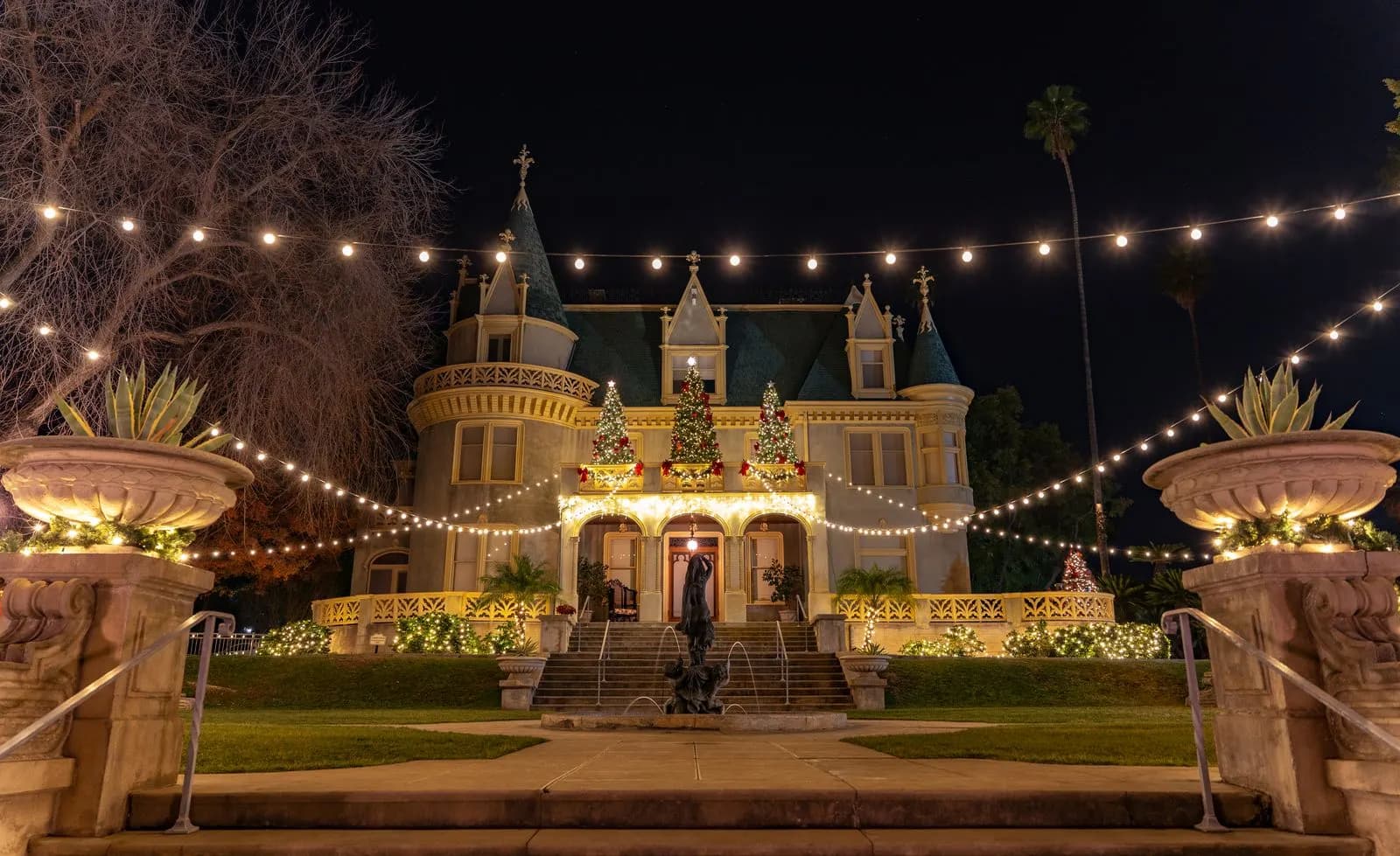 Example of an event venue with overhead string lights, lit garland and decorated trees at the entrance