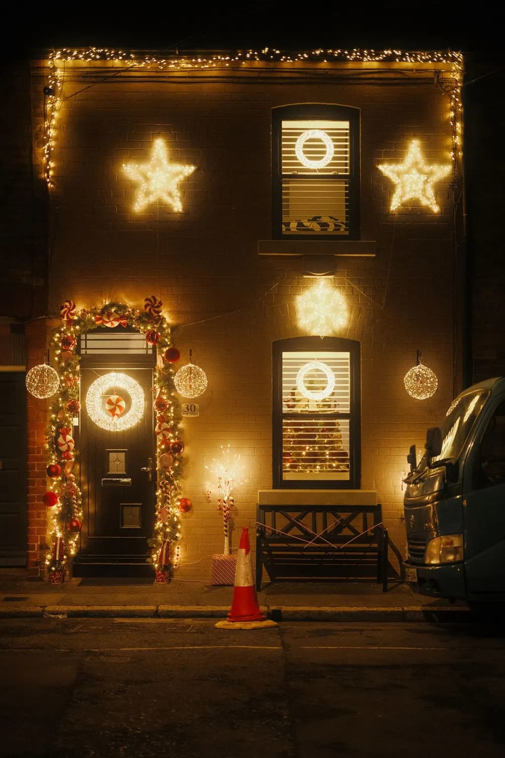 Example of a townhouse with a lit roofline, light-up stars and a garland-framed front door